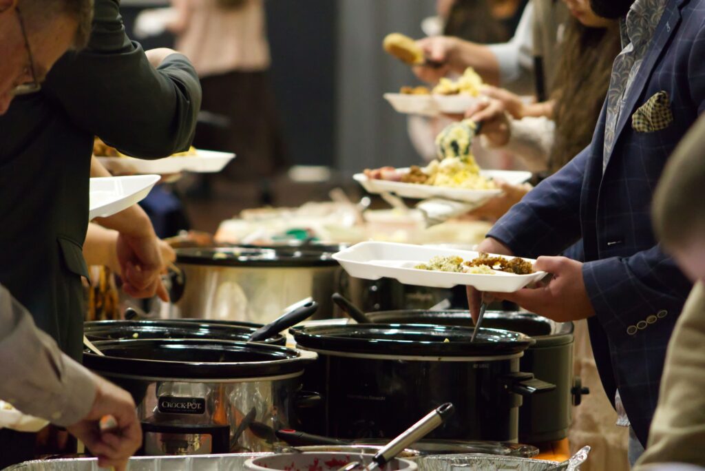 People serving themselves food at a potluck